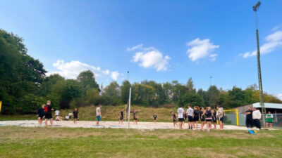 Junge Menschen spielen bei blauem Himmer Beachvolleyball