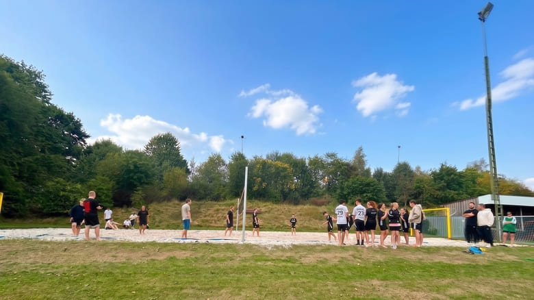 Junge Menschen spielen bei blauem Himmer Beachvolleyball
